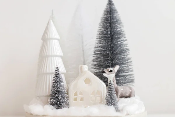 白いテーブルの上にスタイリッシュな小さなクリスマスツリーとトナカイのおもちゃ お祭りのクリスマスシーン かわいい鹿とミニチュアの雪の森 メリークリスマス モダンなテーブル設定 単色の装飾 — ストック写真