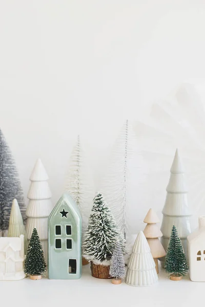 メリークリスマス スタイリッシュな小さなクリスマスツリーと白いテーブルの上の家の装飾 現代のクリスマスシーン ミニチュア雪の村 冬の休日のバナー スキャンディナヴィアのモノクローム装飾 — ストック写真