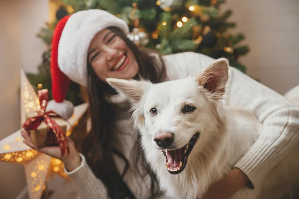 Frohe Weihnachten Glückliche Frau Mit Weihnachtsmütze Umarmt Niedlichen Hund Stilvollen — Stockfoto
