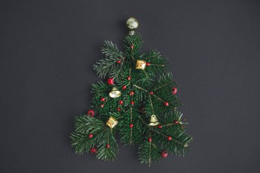 Mutlu Noeller! Köknar dallarından, kırmızı böğürtlenlerden ve siyah arkaplandaki altın takılardan yapılmış şık bir Noel ağacı. Yaratıcı fikir, kış tatili. Modern festival düzlüğü, metin için boşluk