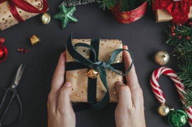 Modern Noel hediyesi. Eller şık bir Noel hediyesi, siyah arka planda yeşil kurdele modern şenlik dekorasyonları, üst manzara. Mutlu Noeller ve mutlu tatiller