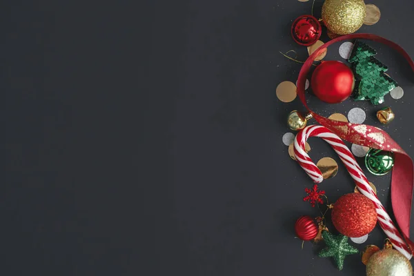 色彩艳丽的圣诞糖果手杖 五彩纸屑和节日装饰品与黑色背景相映成趣 现代圣诞节平平静静地躺着 文字的空间 节日的问候卡片 圣诞快乐及节日快乐 — 图库照片