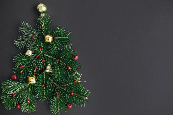 クリスマスツリー 冬の休日の概念 黒い背景にモミの枝 赤い果実と金の泡で作られたスタイリッシュなクリスマスツリー フラットレイアウト 創造的なアイデア 現代のお祝いのバナー — ストック写真
