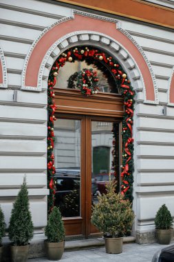 Şık bir Noel çelengi ve dış binalarda kırmızı mücevherlerle süslenmiş köknar dalları. Şehir caddesinde modern noel dekorasyonu. Avrupa 'da kış tatili. Mutlu Noeller.