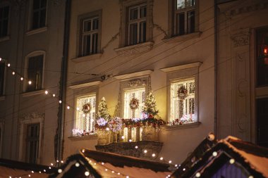 Şık bir Noel şenliği ışıkları, ağaçlar ve akşam balkonda çelenk dekoru. Şehir caddesinde modern noel dekorasyonu. Avrupa 'da atmosferik kış tatili. Mutlu Noeller ve mutlu tatiller