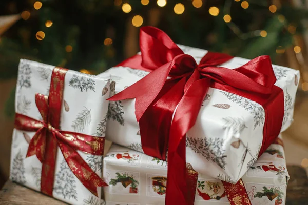 在有灯光的圣诞树前 有一些时髦的圣诞节礼物 圣诞快乐 节日快乐 用红丝带包裹在装饰树下的喜怒无常的房间里的圣诞礼物 大气旗帜 — 图库照片