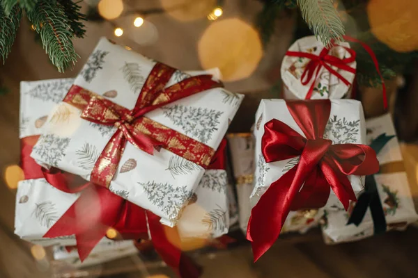 メリークリスマスとハッピーホリデー 黄金のライトボケとクリスマスツリーでスタイリッシュなクリスマスプレゼント 部屋の装飾された木の下に赤いリボンで包まれたクリスマスプレゼント 大気旗 — ストック写真