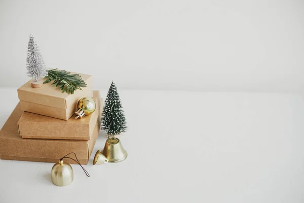 白色桌子上有时尚的生态圣诞礼品盒 简朴的工艺圣诞礼物与金黄色的灌木 树木和枞树分枝在乡村的木材 圣诞快乐 环境友好型假日 文字空间 — 图库照片