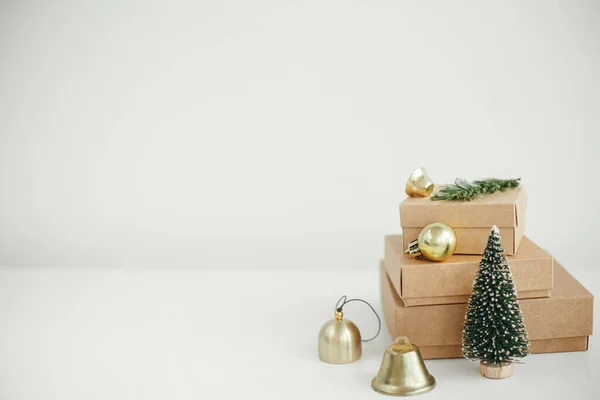白いテーブルの上にスタイリッシュなエコクリスマスギフトボックス 素朴な木の上に黄金の泡 木やモミの枝でシンプルなクラフトクリスマスプレゼント メリークリスマス 環境に優しい休日 テキストのためのスペース — ストック写真