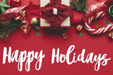 Noel hediyesi, mücevher, köknar dalı, konfeti ve şeker kamışını kırmızı arka planda düzleştiren mutlu bayramlar tabelası. Sezonun tebrik kartı. Noel kartpostalı