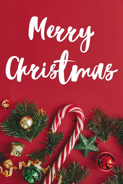 クリスマスの泡 モミの枝 赤い背景のフラットレイアウト上のコンフェッティとキャンディーの杖にメリークリスマスのテキスト シーズンのグリーティングカード 手書きのサイン — ストック写真