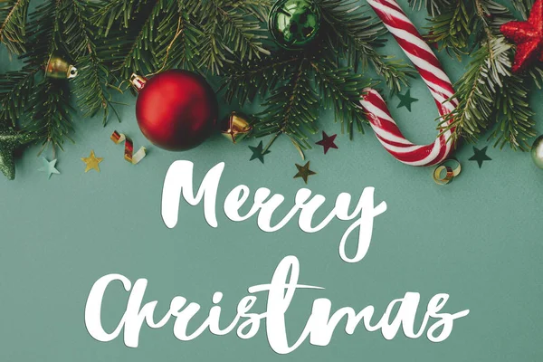 クリスマスのお祝いの装飾 コンフェッティ 緑の背景フラットレイアウト上のモミの枝にメリークリスマステキスト シーズンのグリーティングカード 手書きのサインだ 祭りの絵葉書 — ストック写真
