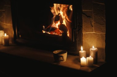 Sıcak bir fincan çay ve mumlar karanlık bir akşam odasında şöminede yanıyor. Evde şömine ısıtması, elektrik kesintisi. Evde şömine başında atmosfer zamanı