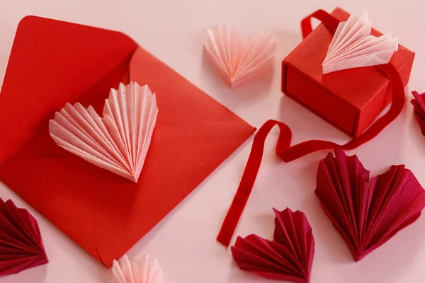 ハッピーバレンタインデー スタイリッシュなピンクのハート 赤い封筒 ピンクの紙の背景にギフトボックス 現代のバレンタインデーの構成 ラブレターのコンセプト — ストック写真