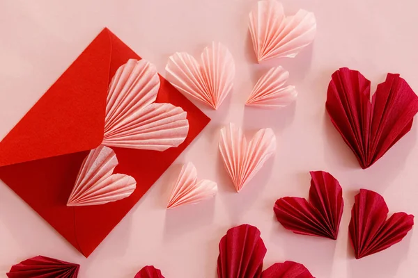 スタイリッシュなピンクのハートとレッドの封筒フラットピンクの紙の背景にレイアウト ハッピーバレンタインデー 現代のバレンタインデーの構成 ラブレターのコンセプト — ストック写真