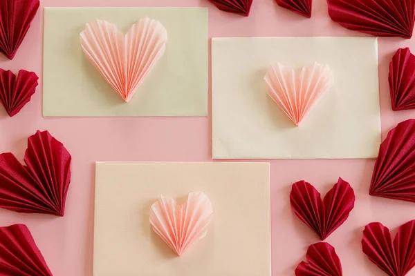 ハッピーバレンタインデー ピンクと赤のハートが入ったスタイリッシュな封筒がピンクの紙の背景に描かれています 現代のバレンタインハートカットアウト ラブレター 創造的な構成 — ストック写真