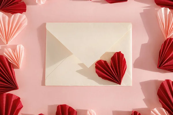 ハッピーバレンタインデー ピンクと赤のハートが入ったスタイリッシュな封筒がピンクの紙の背景に描かれています 現代のバレンタインハートカットアウト ラブレター テキストのためのスペース 創造的な構成 — ストック写真