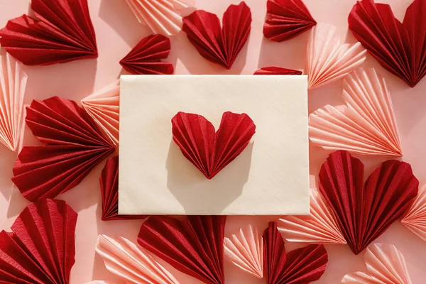 ハッピーバレンタインデー ピンクと赤のハートが入ったスタイリッシュな封筒がピンクの紙の背景に描かれています 現代のバレンタインハートカットアウト ラブレター テキストのためのスペース 創造的な構成 — ストック写真