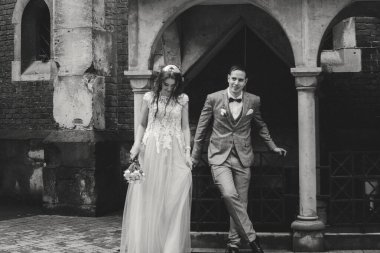 Avrupa şehrindeki güzel bir çiftin bulanık görüntüsü. Tarz sahibi gelin ve damat eski kilisenin arka planında kucaklaşıyorlar. Romantik bir an. Provence düğünü