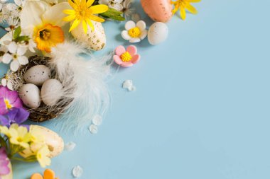 Mutlu Paskalyalar! Yuvada paskalya yumurtaları, renkli çiçekler ve mavi arka planda çiçek açan kiraz yaprakları. Metin için alanı olan şık şablon. Tebrik kartı ya da afiş