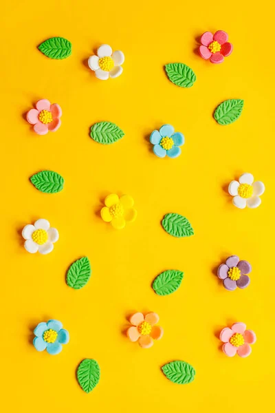 Stylish colorful flowers flat lay on yellow background. Modern festive holiday banner. Spring composition. Happy Easter! Sweet candy flowers and leaves. Greeting card