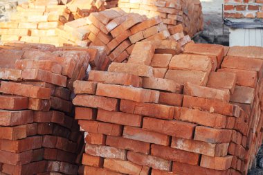 Stack of red bricks, process of house building. Bricks for laying on concrete foundation. Building materials at construction site