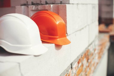 Hard hats on autoclaved aerated concrete blocks at construction site. Architecture and development. Safety helmets on white blocks. House building concept