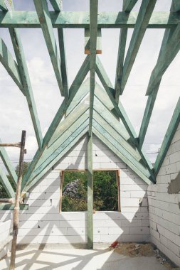 Bitmemiş çatı kirişleri, tavan arasında gökyüzüne karşı kirişler. Ahşap çatı çerçevesi. Modern çiftlik evi inşaatının Mansard 'ı.