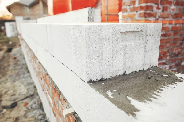 Laying autoclaved aerated concrete blocks with reinforcement and adhesive. Installing white blocks close up. Masonry. Process of house building at construction site
