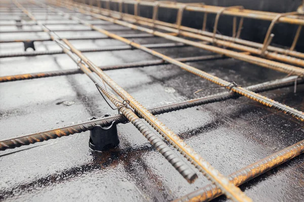 Steel rebar mesh close up. Reinforcement rods at construction site. Rusty steel reinforcement bars for concrete foundation or ceiling. Process of house building