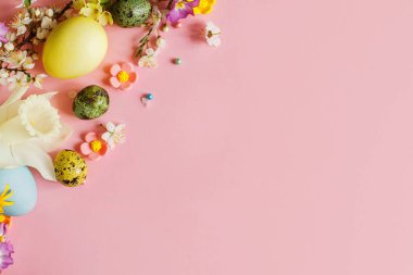 Happy Easter! Easter stylish eggs and blooming spring flowers on pink background, space for text. Modern greeting card or banner. Natural painted colorful eggs and blossom. Easter still life