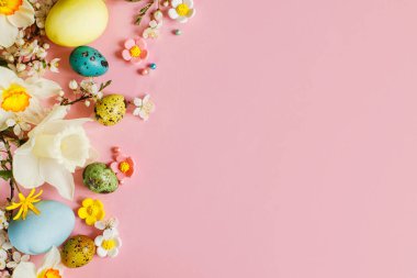 Happy Easter! Easter stylish eggs and blooming spring flowers on pink background, space for text. Modern greeting card or banner. Natural painted colorful eggs and blossom. Easter still life