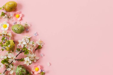 Stylish easter eggs and blooming flowers on pink background flat lay. Happy Easter! Natural painted colorful quail eggs and cherry blossom. Modern greeting card or banner, copy space