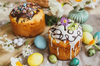 Homemade easter bread and natural dyed easter eggs with spring flowers on linen napkin on rustic table. Traditional Easter food. Happy Easter!