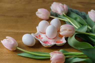 Mutlu Paskalyalar! Ahşap masada güzel laleler ve yumurtalar. Modern çiftlik evi paskalya dekoru. Doğal yumurta ve pembe laleli el yapımı yumurta tutacağı.