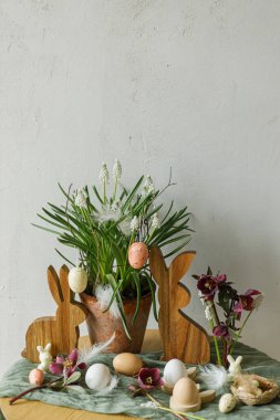 Mutlu Paskalyalar! Şık ahşap tavşancık, bahar çiçekleri, kırsal masadaki doğal yumurta ve tüyler. Paskalya 'da hayat. Çiftlik evinde şenlik düzenleme ve dekor