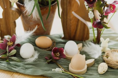 Paskalya 'da hayat. Şık ahşap tavşan kulakları ve doğal yumurtalar, bahar çiçekleri, tüyler ve kırsal masada yuva. Mutlu Paskalyalar! Çiftlik evinde şenlik düzenleme ve dekor