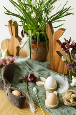 Paskalya 'da hayat. Şık ahşap tavşancık, bahar çiçekleri ve kırsal masadaki doğal yumurtalar. Mutlu Paskalyalar! Çiftlik evinde şenlik düzenleme ve dekor