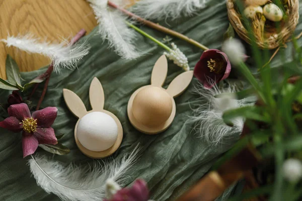 ハッピーイースター スタイリッシュな木製のウサギの耳と自然卵 春の花 羽や素朴なテーブルの上に巣を閉じます イースターはまだ生きてる 農家でのお祭りの配置と装飾 トップビュー — ストック写真