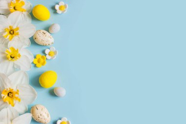 Mutlu Paskalyalar! Paskalya yumurtaları ve sarı nergis çiçekleri mavi arka planda yatıyordu. Metin için alanı olan şık şablon. Tebrik kartı ya da afiş