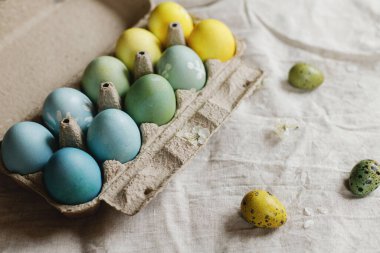 Paskalya yumurtaları ve kiraz dalı kırsal masada. Mutlu Paskalyalar! Kırsal Paskalya natürmortu. Kağıt tepside doğal boyanmış yumurtalar ve keten kumaşta bahar çiçekleri.