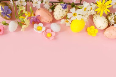 Happy Easter! Easter flat lay with stylish eggs and blooming spring flowers on pink background. Modern template with space for text. Greeting card or banner. Festive border