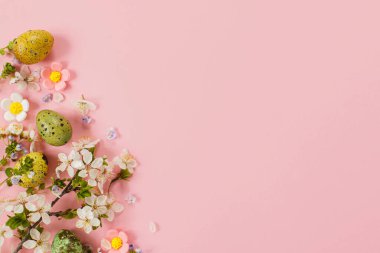 Happy Easter! Easter stylish eggs and blooming spring flowers on pink background, space for text. Modern greeting card or banner. Natural painted colorful quail eggs and cherry blossom