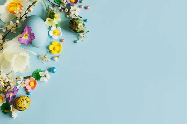 ブルーの背景には おしゃれなイースターエッグやキャンディ 花を咲かせます ハッピーイースター 天然の色鮮やかな卵と春の花を描いた 現代のグリーティングカードやバナー コピースペース — ストック写真