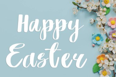 Mutlu Paskalya tebrik kartları. Şekerleme ve çiçek açan kiraz dalları üzerine Mutlu Paskalya metinleri mavi arka planda yatıyordu. Modern tebrik kartı. El yazısı işareti