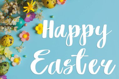 Mutlu Paskalya tebrik kartları. Paskalya 'daki mutlu paskalya metinleri şık yumurtalar ve mavi arka planda çiçek açan bahar çiçekleriyle yatıyordu. Modern tebrik kartı. El yazısı işareti