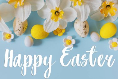 Mutlu Paskalya tebrik kartları. Paskalya yumurtaları ve sarı nergis çiçekleri üzerine Mutlu Paskalya metinleri mavi arka planda yatıyordu. Modern tebrik kartı. El yazısı işareti