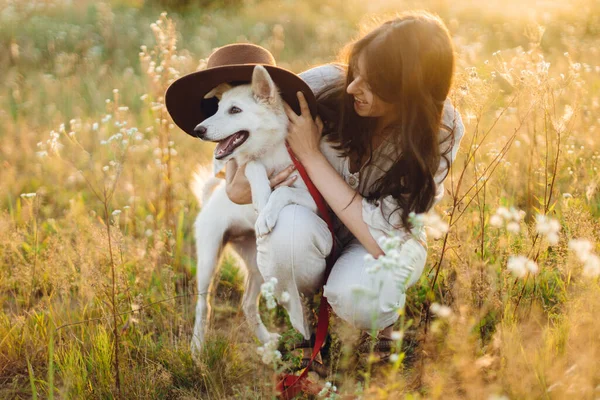 Stylowa Szczęśliwa Kobieta Gra Cute Dog Kapeluszem Wśród Dzikich Kwiatów — Zdjęcie stockowe