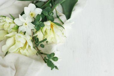 Anneler Günün kutlu olsun. Güzel beyaz laleler ve yumuşak kumaş üzerinde nergisler. Kırsal ahşap masa üzerinde yazı için yeri olan. Bahçeden güzel bir bahar buketi. Kadınlar Günü