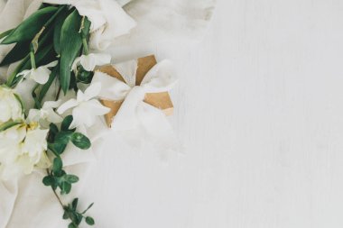 Anneler Günün kutlu olsun. Kırsal ahşap masa üzerinde hediye kutusu olan güzel beyaz bir buket. Yumuşak kumaşlı bahar laleleri ve nergisler. Kadınlar Günü 'nde. Metin için boşluk